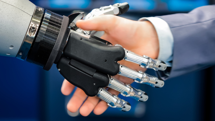 Hand of a businessman shaking hands with a droid robot. The concept of human interaction with artificial intelligence.