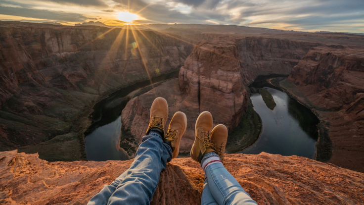 Personal perspective of couple relaxing on top of Grand Canyon; feet view; People travel vacations relaxation concept