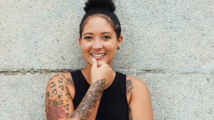 Laughing hipster girl with tattoos and piercing in urban style