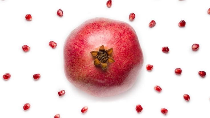 ripe-pomegranate-in-the-center-and-fruit-pomegranate-seeds-scattered-picture-id1049910412